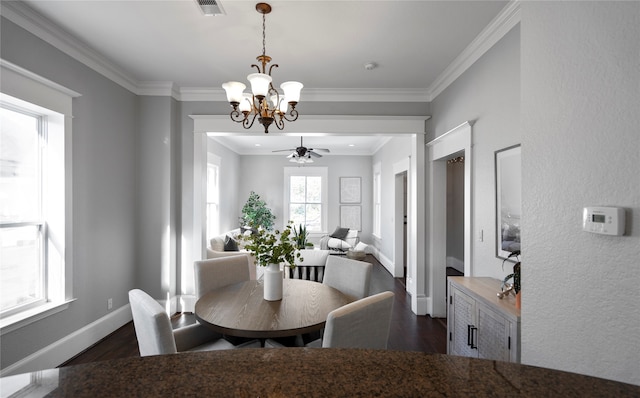 dining room with crown molding, dark wood-type flooring, and ceiling fan with notable chandelier