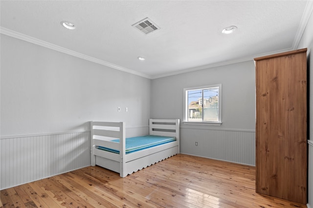 unfurnished bedroom featuring crown molding, light hardwood / wood-style flooring, a textured ceiling, and wooden walls