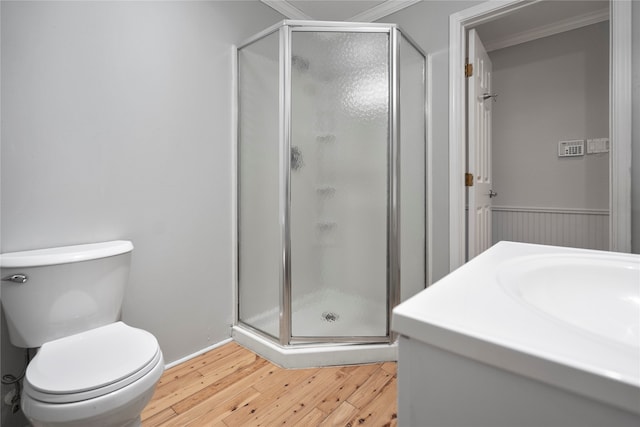 bathroom featuring hardwood / wood-style flooring, toilet, crown molding, vanity, and an enclosed shower