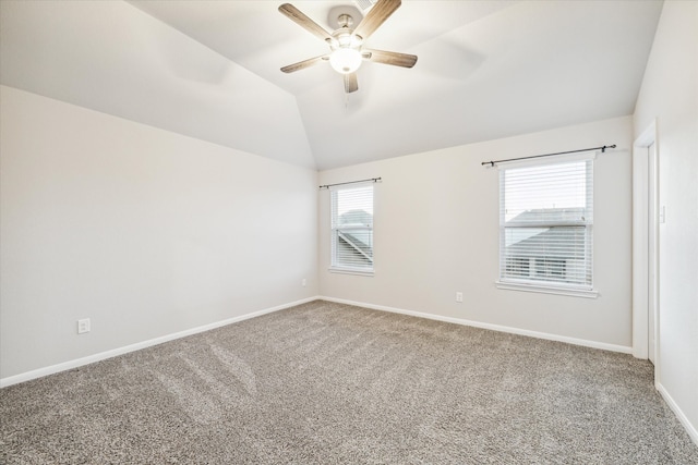 carpeted empty room with ceiling fan, vaulted ceiling, and plenty of natural light