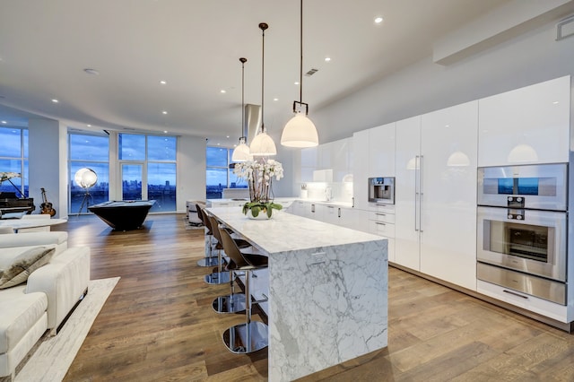 kitchen featuring pool table, a breakfast bar, white cabinetry, light wood-type flooring, and decorative light fixtures