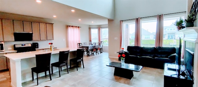 kitchen featuring black appliances, sink, a breakfast bar, light brown cabinets, and a center island with sink