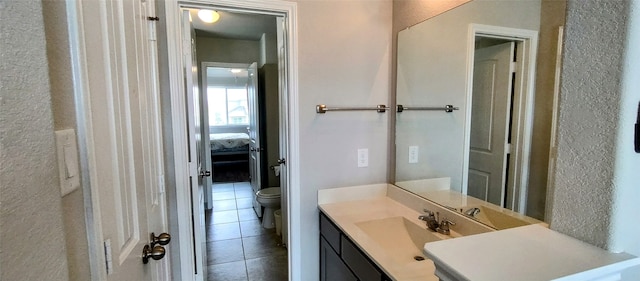 bathroom with toilet, vanity, and tile patterned flooring