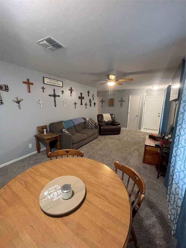 carpeted dining space featuring ceiling fan and a textured ceiling