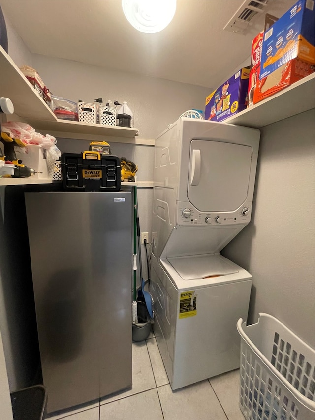 clothes washing area with stacked washer / drying machine and light tile patterned floors