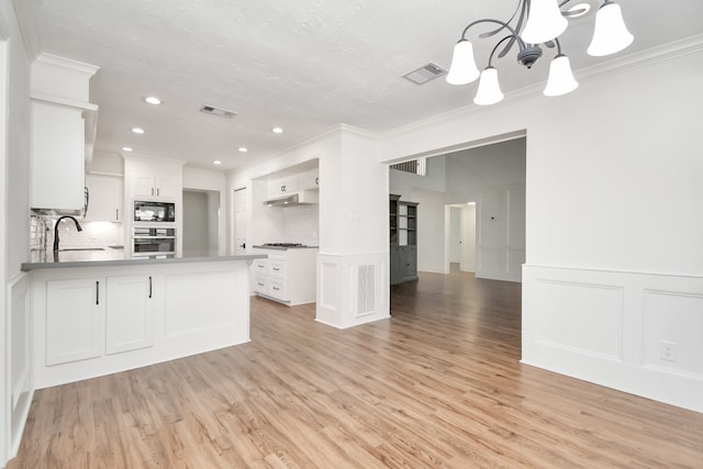 kitchen featuring appliances with stainless steel finishes, light hardwood / wood-style flooring, white cabinetry, and tasteful backsplash