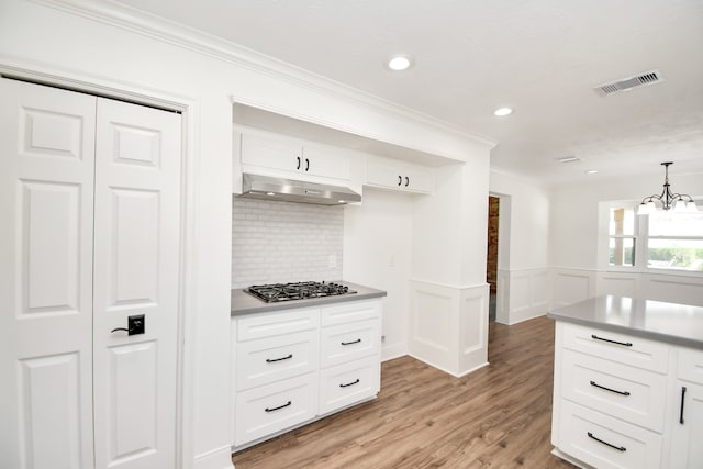 kitchen with stainless steel gas stovetop, hanging light fixtures, light hardwood / wood-style flooring, white cabinetry, and a chandelier