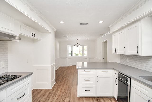 kitchen with white cabinetry, an inviting chandelier, tasteful backsplash, kitchen peninsula, and light hardwood / wood-style floors