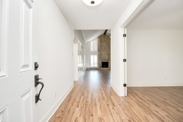 corridor featuring lofted ceiling, light hardwood / wood-style floors, and ornamental molding