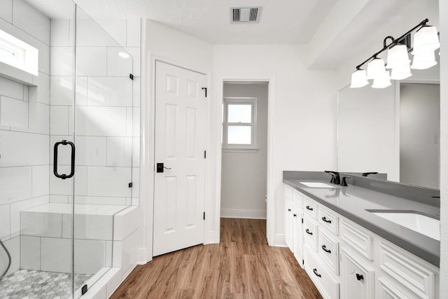 bathroom with hardwood / wood-style floors, vanity, and an enclosed shower