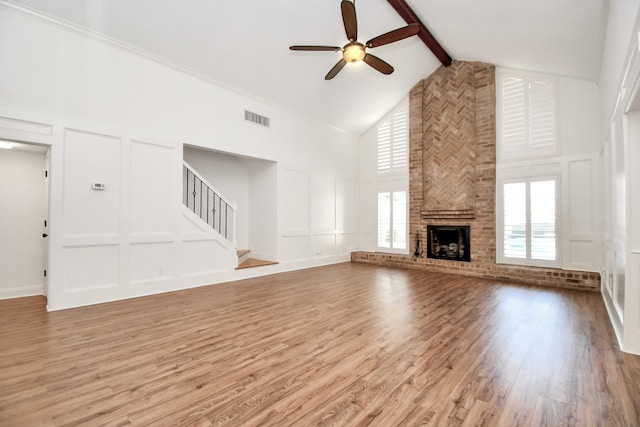 unfurnished living room with high vaulted ceiling, ceiling fan, light wood-type flooring, a fireplace, and beamed ceiling