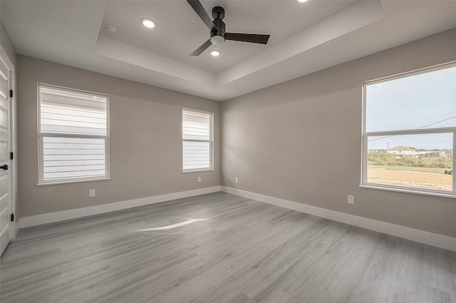 unfurnished room featuring ceiling fan, light hardwood / wood-style flooring, and a tray ceiling