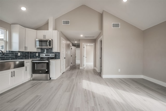 kitchen with appliances with stainless steel finishes, sink, decorative backsplash, light hardwood / wood-style floors, and white cabinets