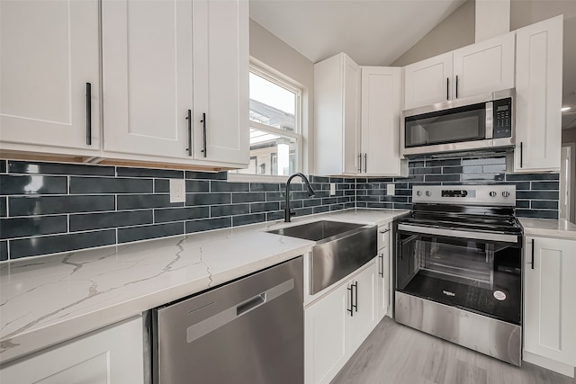 kitchen featuring white cabinets, stainless steel appliances, sink, and backsplash