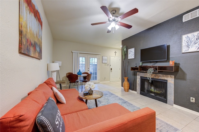 living room featuring french doors, ceiling fan, light tile patterned floors, and a tile fireplace