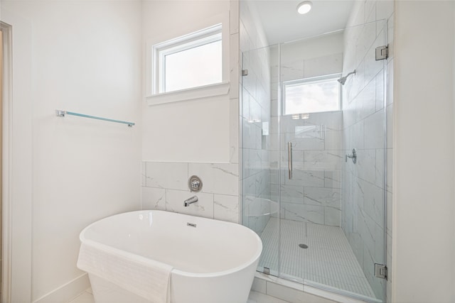 bathroom with a wealth of natural light, separate shower and tub, and tile walls