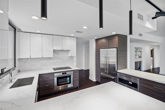 kitchen featuring white cabinetry, dark brown cabinetry, stainless steel appliances, and sink