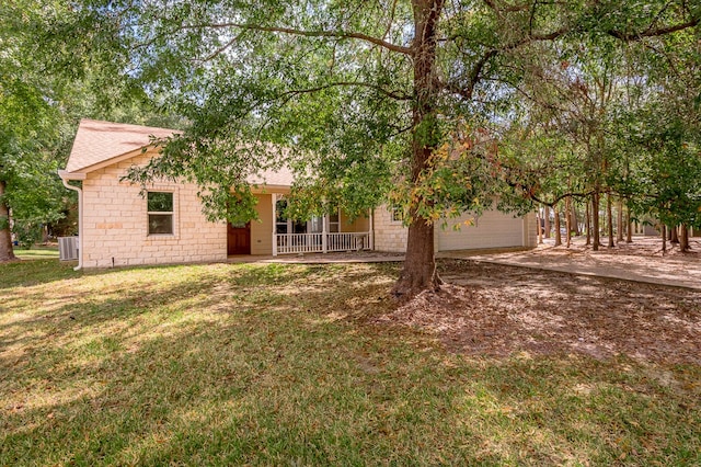 view of front of home featuring a garage, a front lawn, central AC unit, and a porch