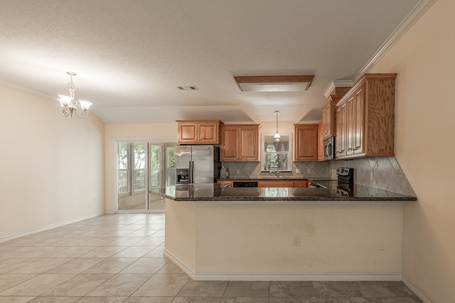 kitchen featuring stainless steel appliances, tasteful backsplash, dark stone counters, and hanging light fixtures