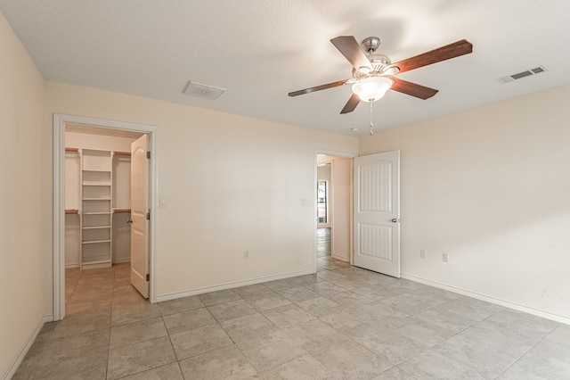 empty room featuring ceiling fan, a textured ceiling, and light tile patterned floors