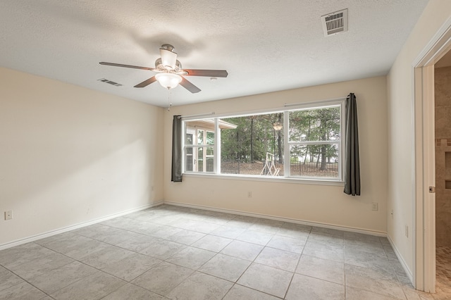 spare room with a textured ceiling, light tile patterned floors, and ceiling fan