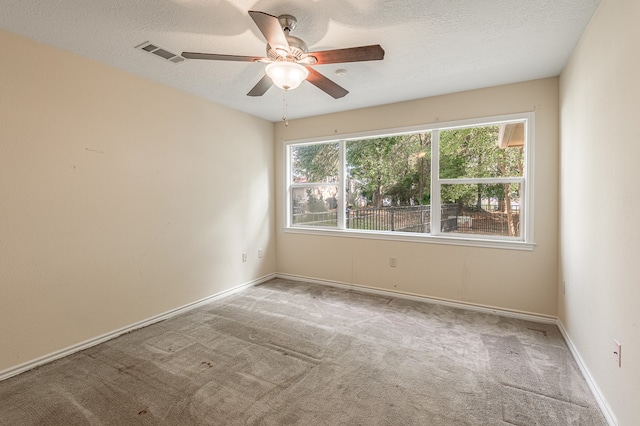 empty room featuring a textured ceiling, light colored carpet, and ceiling fan