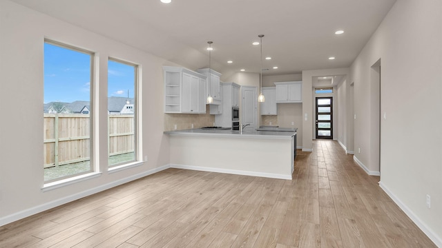 kitchen with hanging light fixtures, a wealth of natural light, white cabinetry, and light hardwood / wood-style floors