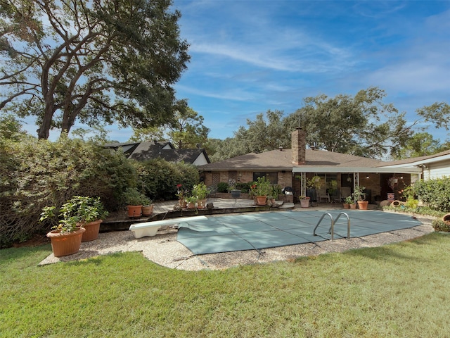 view of swimming pool featuring a patio area, a diving board, and a lawn