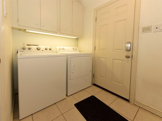 washroom with light tile patterned flooring, washer and dryer, and cabinets