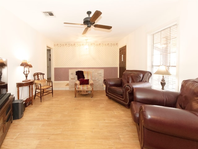 living room with light hardwood / wood-style flooring, a fireplace, and ceiling fan