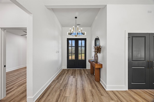 entryway with french doors, light wood-type flooring, and a notable chandelier