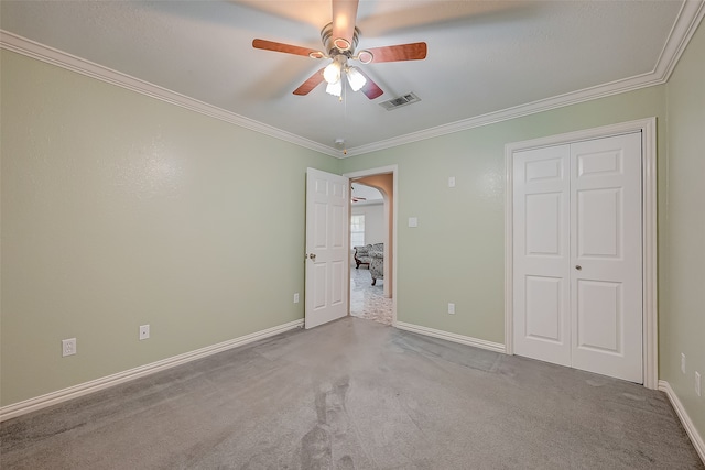 unfurnished bedroom with a closet, ceiling fan, light carpet, and crown molding