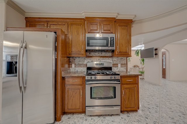 kitchen with light tile patterned floors, appliances with stainless steel finishes, backsplash, light stone countertops, and crown molding