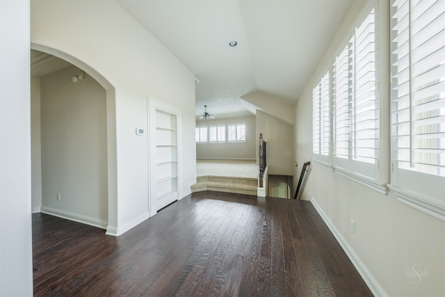 interior space featuring built in shelves, dark hardwood / wood-style floors, and vaulted ceiling