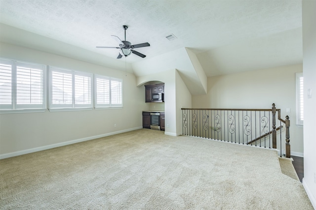 interior space with carpet, a textured ceiling, vaulted ceiling, and beverage cooler