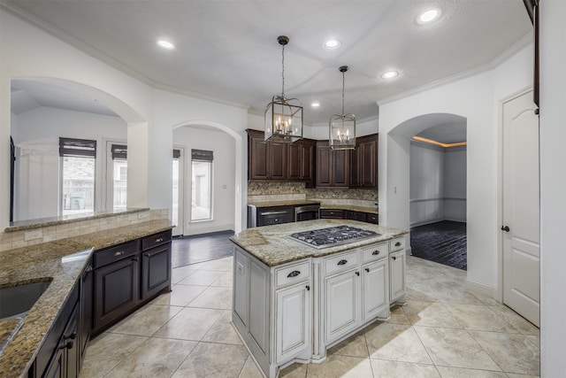 kitchen with tasteful backsplash, dark brown cabinets, crown molding, white cabinetry, and stainless steel gas stovetop