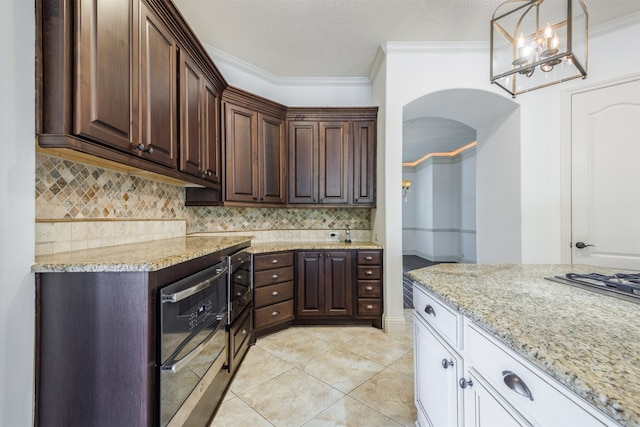 kitchen featuring white cabinetry, backsplash, decorative light fixtures, light tile patterned floors, and ornamental molding