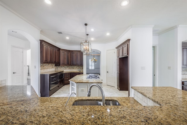 kitchen featuring ornamental molding, dark brown cabinets, sink, a notable chandelier, and a center island