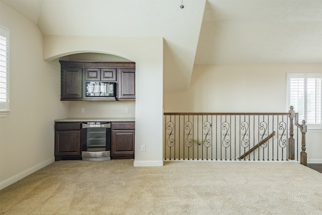 bar featuring dark brown cabinetry, light carpet, beverage cooler, and vaulted ceiling