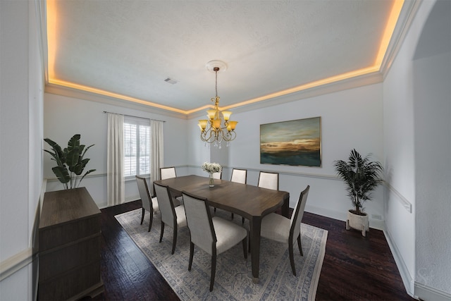 dining area featuring a tray ceiling, dark wood-type flooring, and a notable chandelier