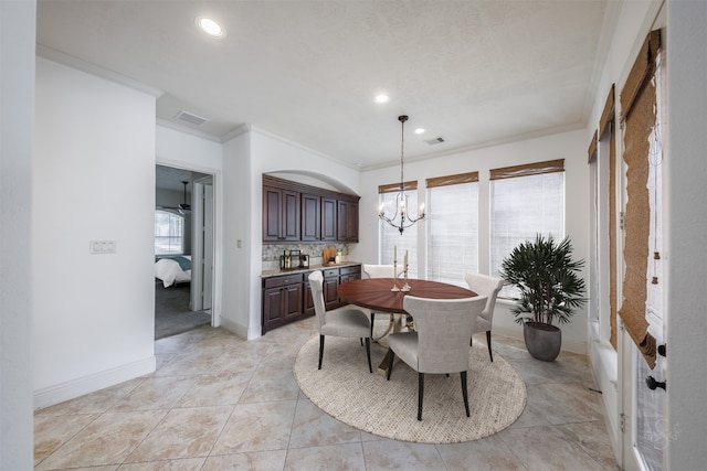 dining room featuring a healthy amount of sunlight, ornamental molding, light tile patterned floors, and an inviting chandelier