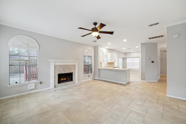 unfurnished living room with ornamental molding, a premium fireplace, and ceiling fan