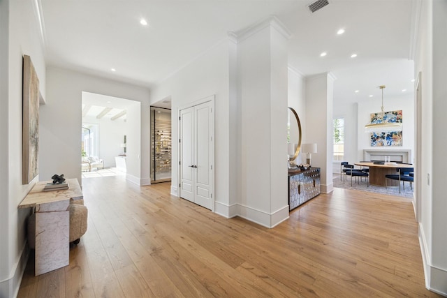 hall featuring ornamental molding and light hardwood / wood-style flooring