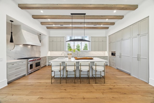 1944 Larchmont Rd, Houston, TX 77019 - kitchen featuring double oven range, a breakfast bar area, a center island with sink, custom exhaust hood, and gray cabinets