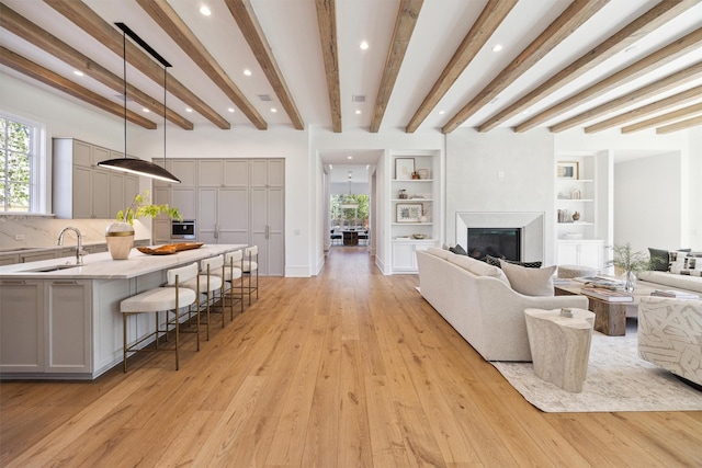 1944 Larchmont Rd, Houston, TX 77019 - living area featuring light wood-style floors, beamed ceiling, a glass covered fireplace, recessed lighting, and built in features