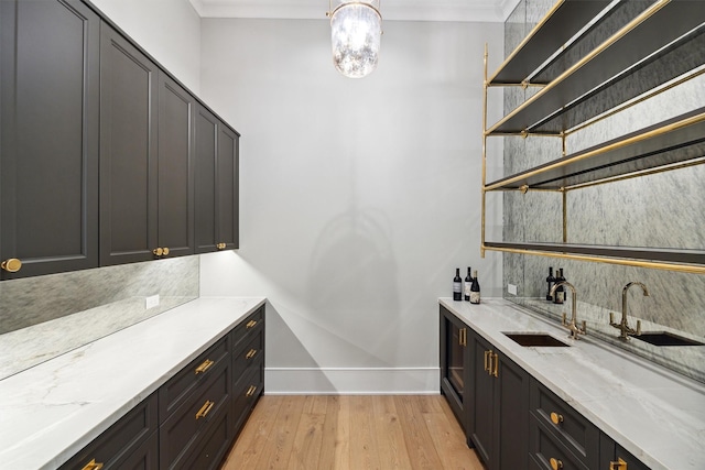 1944 Larchmont Rd, Houston, TX 77019 - indoor wet bar with light wood-type flooring, baseboards, crown molding, a chandelier, and tasteful backsplash
