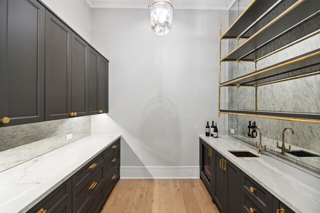 1944 Larchmont Rd, Houston, TX 77019 - indoor wet bar with light wood-style flooring, crown molding, a chandelier, and decorative backsplash