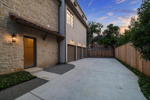 1944 Larchmont Rd, Houston, TX 77019 - view of home's exterior featuring stone siding, a garage, and concrete driveway