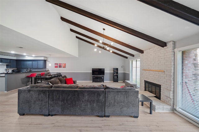 living room with a chandelier, lofted ceiling with beams, light hardwood / wood-style floors, and plenty of natural light