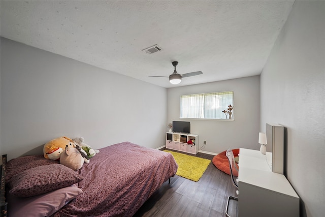 bedroom with ceiling fan, a textured ceiling, and dark hardwood / wood-style floors